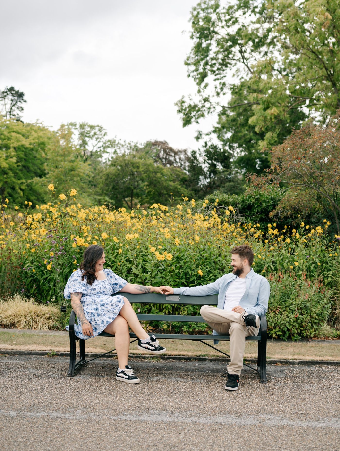 Steph and Jonny smiling at each other on a garden bench in front of yellow flowers
